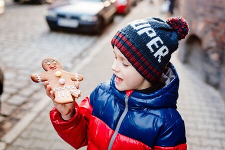Little 7 years old boy eating Gingerbread Man - Christmas symbol