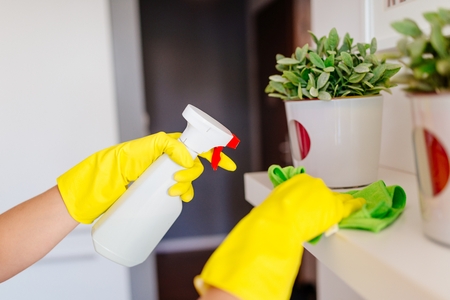 Woman wearing yellow rubber protective gloves and cleaning white shelf. MORE FROM THIS SERIES IN MY...