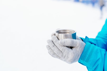 Woman holding hot tea in metal mug at winterの写真素材
