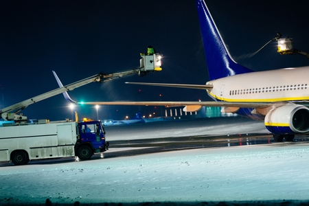 Deicing passenger airplane during heavy snow at nightの写真素材