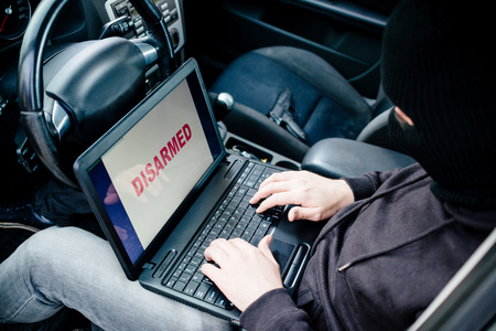 Car thief trying to break car security systems with laptop computer. Car thief, car theftの写真素材