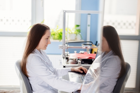 Woman in a white lab coat designs item to three dimensional printing. 3d printing
