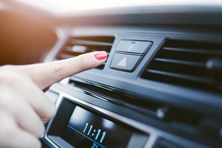 Woman turns on the emergency lights in the car. Modern car interior