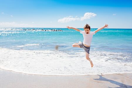 Happy 7 years boy jumping on the beach. Tenerife, Playa del Duque, Costa Adejeの写真素材