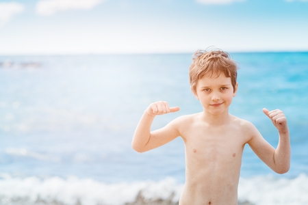 Happy 7 years boy in victory success gesture on the beach. Tenerife, Playa del Duque, Costa Adejeの写真素材