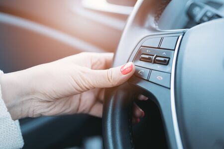 Closeup photo of woman pressing green phone control button on car steering wheelの写真素材