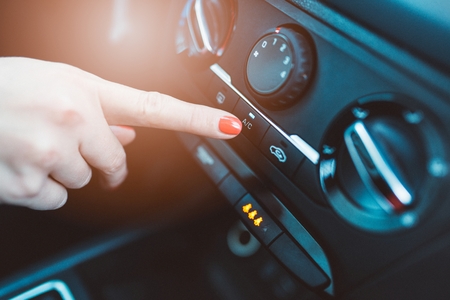Woman turns on air conditioning in her car. Modern car interiorの写真素材