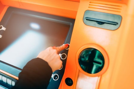 Woman getting money from an ATM. Choosing optionsの写真素材