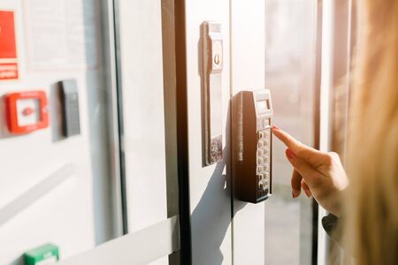Woman entering pin code to security system in office