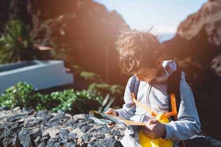 Little boy child with backpack reading map in mountains. Masca Valley, Tenerife island, Canary Islands, Spainの写真素材
