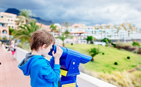 Little boy child playing with public pay telescope. Adeje, Tenerife, Canary Islands, Spainの写真素材