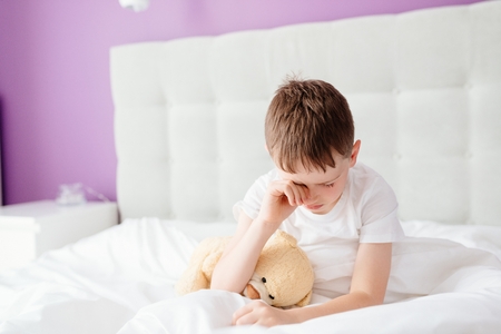 Little boy child waking up at the morning. Hugging his favourite teddy bearの写真素材