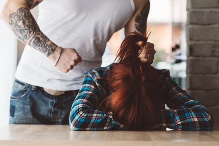 Woman victim of domestic violence threatened by her husband. Man about to beat his wifeの写真素材