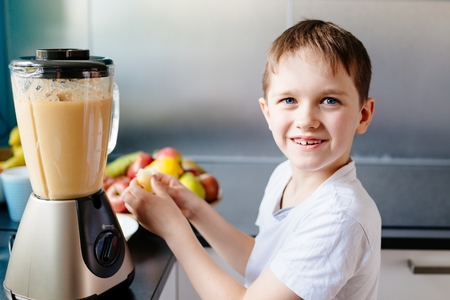 Happy little boy is making healthy fruit juice at home. Healthy eatingの写真素材