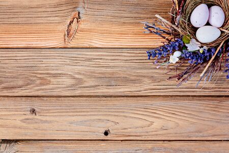 Easter eggs in nest on rustic wooden background with space for message. Happy Easter