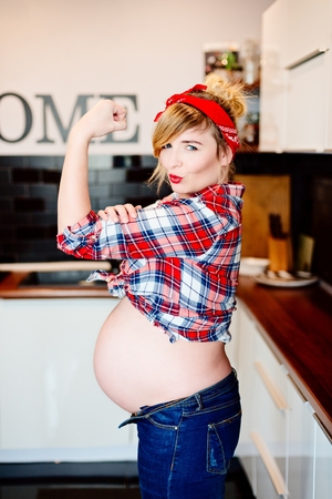 Young beautiful happy pregnant woman in kitchen. Pin up styleの写真素材