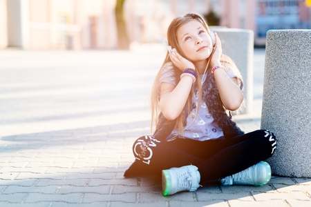10 years old happy girl child listen to the music. Sunny day at cityの写真素材