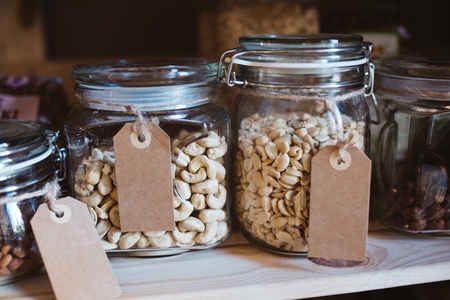 Cashew nuts and peanuts in glass jars with label in a shop with natural organic food.の写真素材