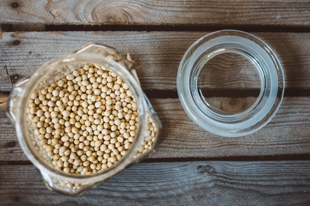 Glass jar with yellow soya on rustic wooden backgroundの写真素材
