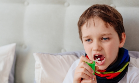 Little boy child inhaling his throat with spray inhaler. Sick child