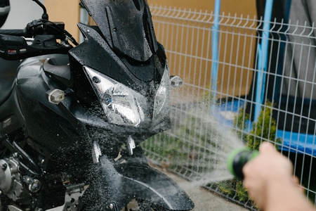 Cleaning black touristic motorbike with waterの写真素材