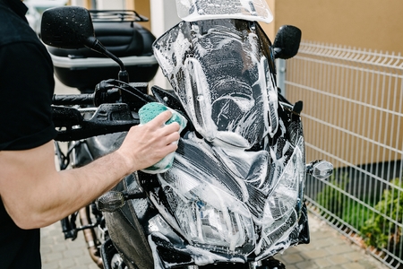 Cleaning black touristic motorbike with water and spongeの写真素材