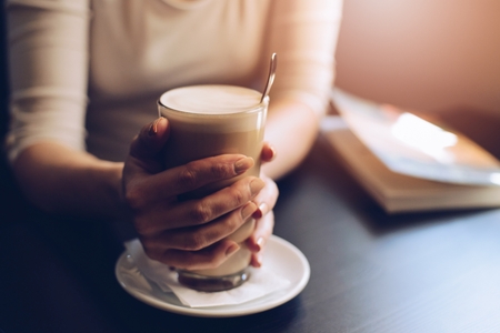 Woman cafe customer enjoying her coffee and reading a bookの写真素材
