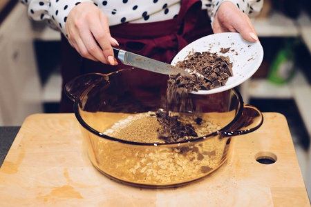 Cafe employee adding pieces of chocolate to bowl . Woman prepares delicious, healthy cookies from spelt flour, oatmeal and chocolateの写真素材