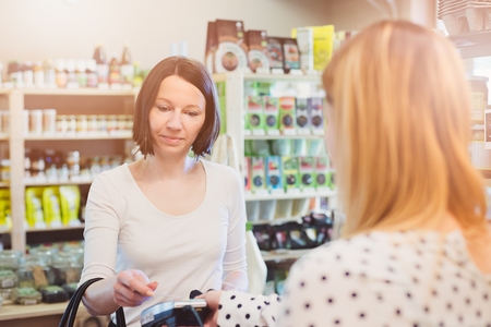 Woman paying with contactless credit card in shopの写真素材