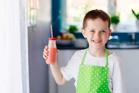 Child drinking strawberry banana cocktail from bootle glass with strawの写真素材