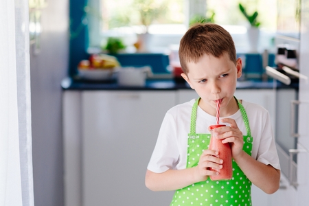 Child drinking strawberry banana cocktail from bootle glass with strawの写真素材