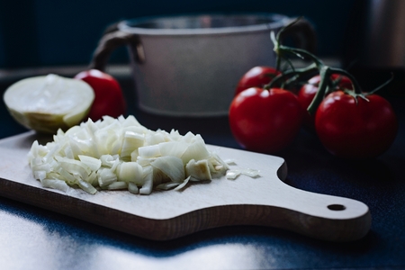 Chopped onion on a wooden chopping board in the kitchen. Preparing dinnerの写真素材