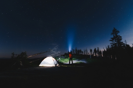 Man tourist with flashlight near his camp tent at night. Malinowska Skala. Szczyrk. Silesian Beskid, Polandの写真素材
