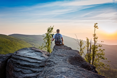 Man tourist sitting on top of hill at sunrise. Early morning. Malinowska Skala, Szczyrk, Silesian...