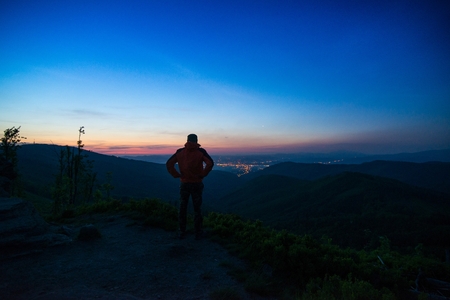 Man tourist standing on mountaintop observing city lights. Zywiec, Malinowska Skala. Szczyrk. Silesian Beskid, Polandの写真素材