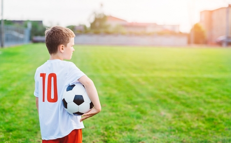 8 years old boy child holding football ball on playing field. Child playing footballの写真素材
