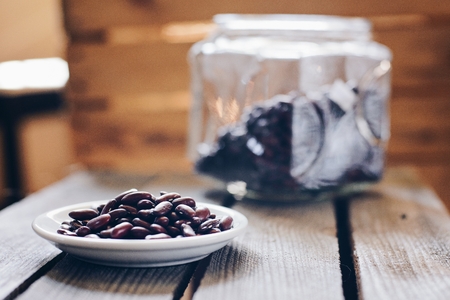 Raw red kidney beans on small plate on wooden background. Healthy diet food