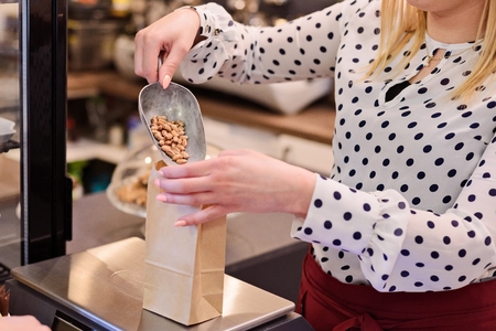 Woman pouring pinto bean to paper paper bag in a shopの写真素材