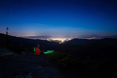 Alone man tourist hiker looking on city lights from the hill at night. Zywiec, Silesian Beskid, Silesia, Polandの写真素材