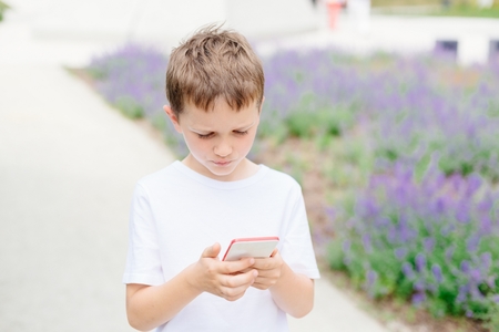 Child boy playing mobile games on his smartphone at city