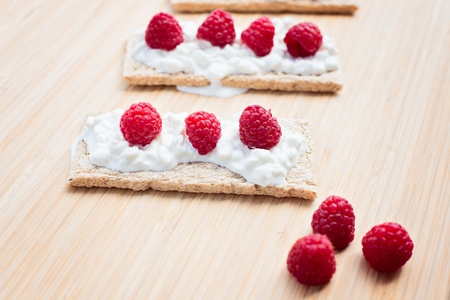 Crunchy rye-wheat bread with white cottage cheese and raspberries. Delicious diet healthy snack.の写真素材