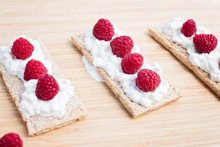 Crunchy rye-wheat bread with white cottage cheese and raspberries. Delicious diet healthy snack.の写真素材