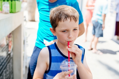 Little child boy drinking healthy fruit smoothie at sunny summer dayの写真素材