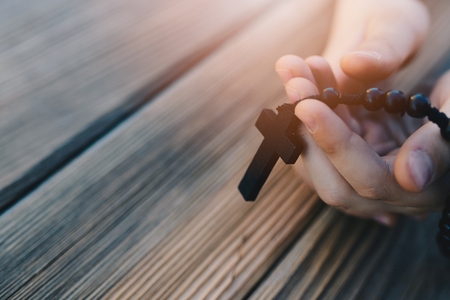 Little childs hands holding wooden rosary. Child prayingの写真素材