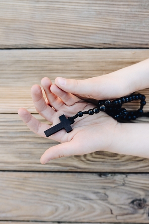 Little childs hands holding wooden rosary. Child prayingの写真素材