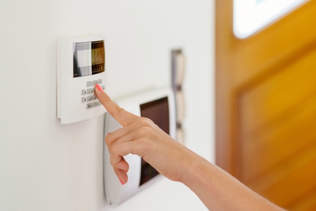 Young woman entering authorization code pin on home alarm keypad. Home security conceptの写真素材