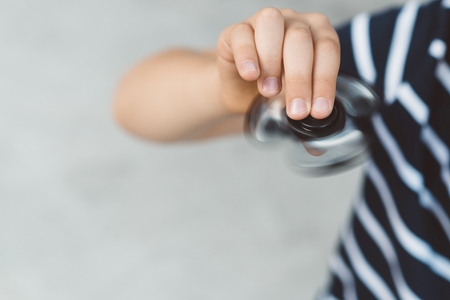 Little child boy playing with fidget spinner outdoors - popular plastic toyの写真素材