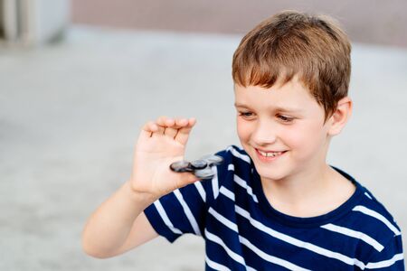 Little child boy playing with fidget spinner outdoors - popular plastic toyの写真素材
