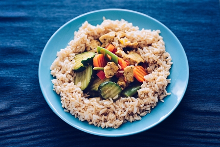 Fried chicken with brown rice and vegetables on the plate.の写真素材