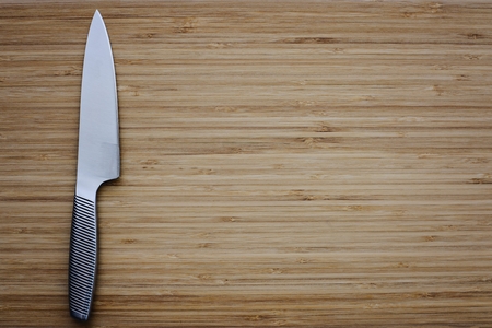 Stainless kitchen knife on empty cutting board. Copy space for messageの写真素材